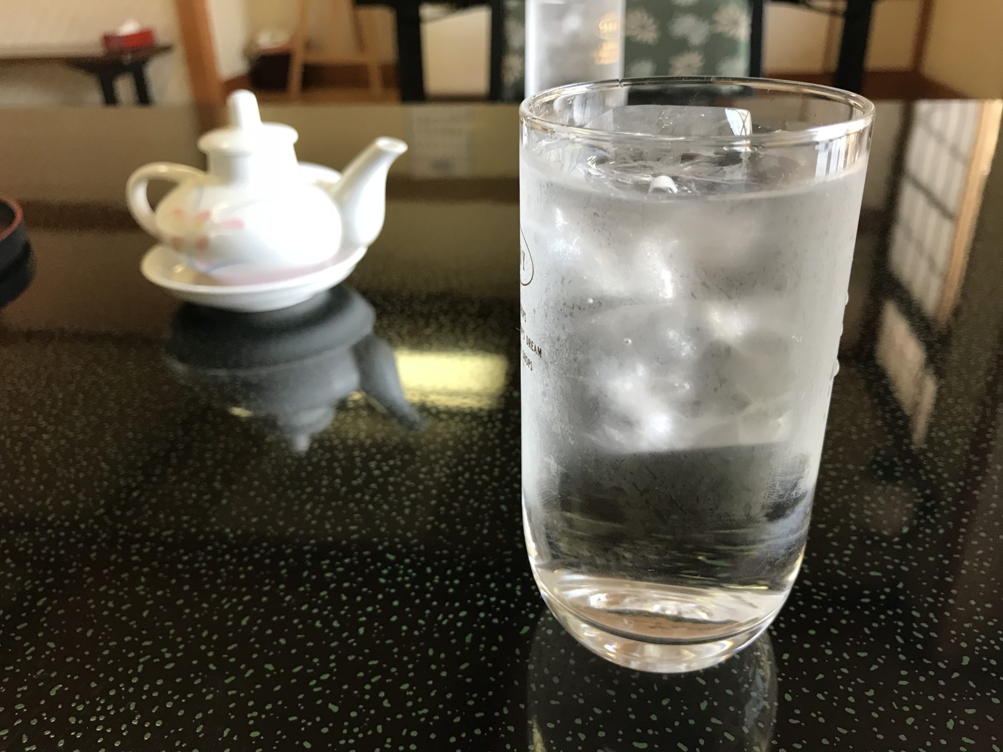 机の上の冷たい水が入ったコップ